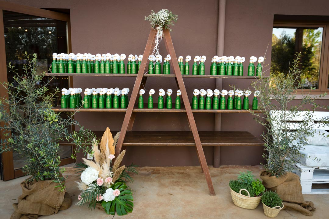 Aceite de oliva como regalo de boda. Fotografía de la boda de Sara y Marc, de Mas dels Castellans. Stand con botellas de aceite para los invitados.